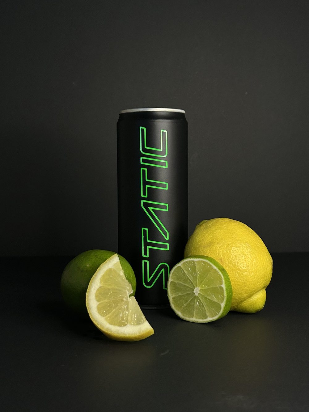 A black Static can with the green outlined logo, surrounded by cut limes and a lemon